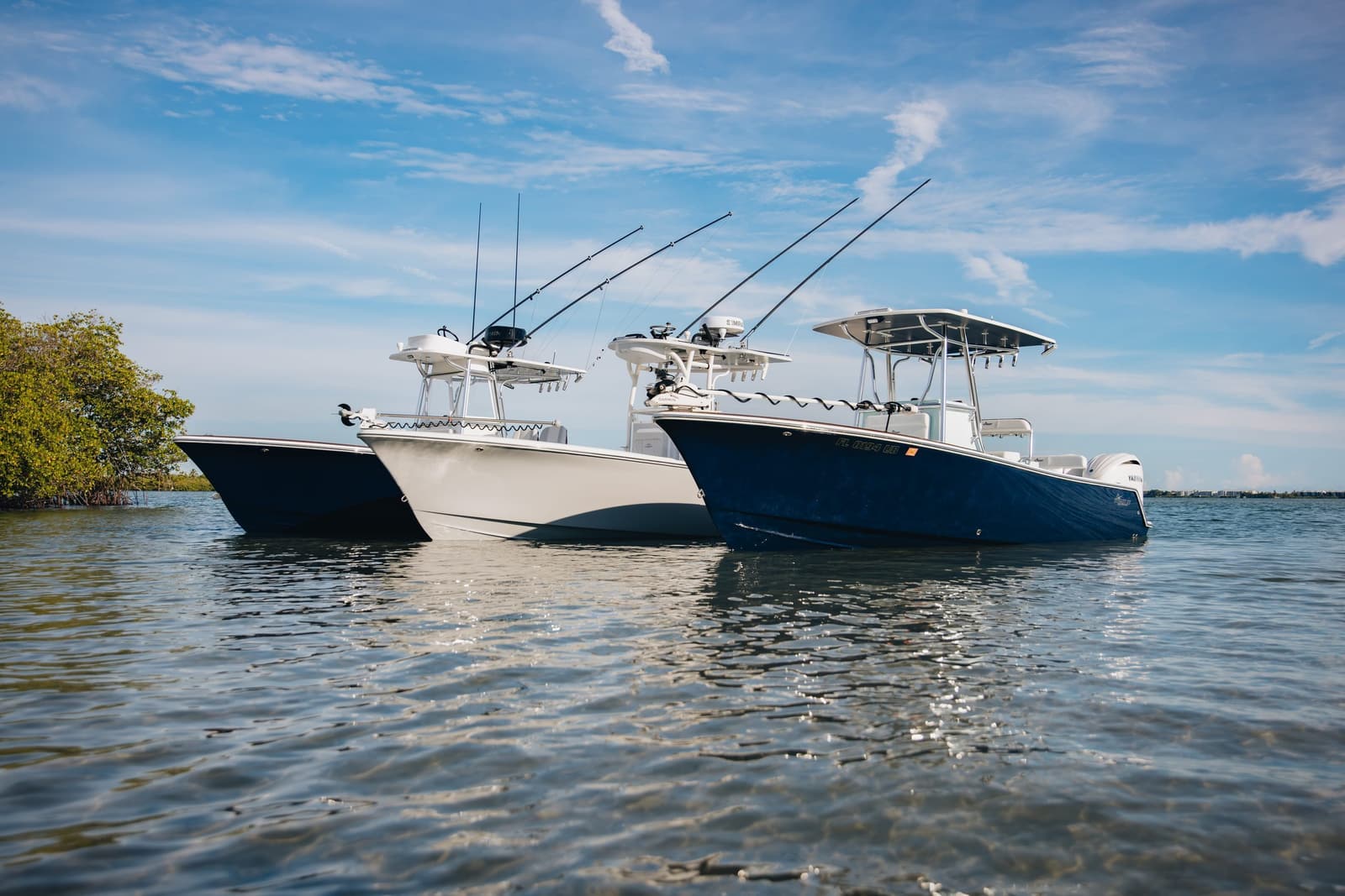 Three Stuart center consoles anchored in a row in shallow water